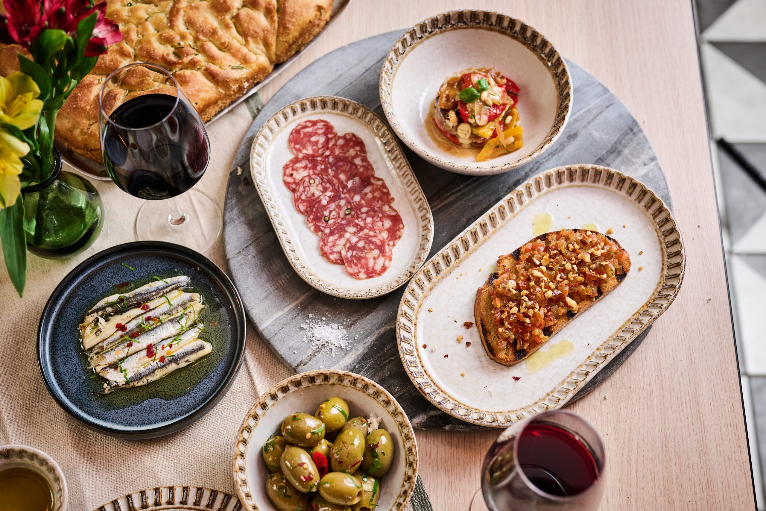 Dishes on wooden table with a glass of red wine.